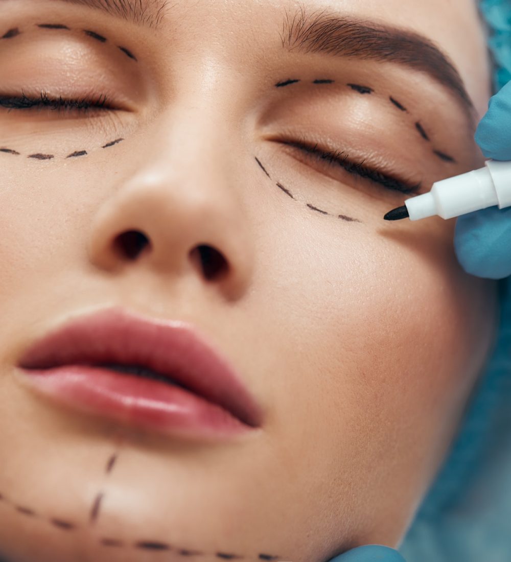 Close up photo of young woman with glowing skin in blue medical hat waiting for facial surgery